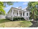 Charming white home with a covered porch, columns, and lush landscaping at 300 Ginned Cotton St, Charleston, SC 29492