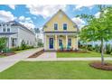Charming yellow two-story home with a blue door, inviting porch, and freshly manicured lawn at 403 Ripple Park Dr, Summerville, SC 29486