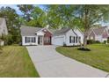 Charming single-story home with a well-manicured lawn, long driveway, and attached garage at 4872 Law Blvd, Summerville, SC 29485
