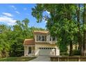 Traditional-style home with a 2-car garage, and a welcoming front porch, surrounded by lush trees, and a beautiful lawn at 675 Fair Spring Dr, Charleston, SC 29414
