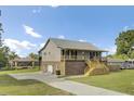 The side view reveals a home with a brick foundation, and a metal roof, complemented by a spacious driveway and lush lawn at 108 Mourning Dove Dr, Bonneau, SC 29431