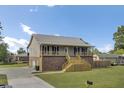 The side view shows a home with a brick foundation, and a metal roof, a spacious driveway, and a well-manicured lawn at 108 Mourning Dove Dr, Bonneau, SC 29431
