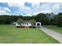Picture perfect single-Gathering home from above, showing a white exterior, detached garage, and a sprawling manicured lawn at 131 Travis Hill Rd, Moncks Corner, SC 29461