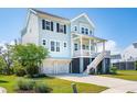 Charming light blue raised beach home with a two-car garage and a stairway to the covered front porch at 1502 Menhaden Ln, Mount Pleasant, SC 29466