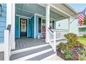 Inviting front porch with black door, rocking chair, American flag, and a beautifully landscaped garden at 1511 Hopkins Ln, Mount Pleasant, SC 29466