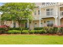 Charming two-story home with a pergola, lush greenery, and vibrant pink roses in the landscaped yard at 1825 Brittlebush Ln, Johns Island, SC 29455