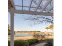 Scenic lake view framed by a pergola, showcasing waterfront homes and palm trees in the distance at 1825 Brittlebush Ln, Johns Island, SC 29455