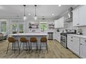 Bright kitchen featuring white cabinets, a large island with bar seating, stainless steel appliances and laminate floors at 3361 Olivia Marie Ln, Johns Island, SC 29455