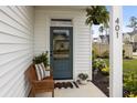 Inviting front porch with a cozy wooden bench, plants, and a 'Welcome Home' doormat at 401 Carrara Dr, Summerville, SC 29486