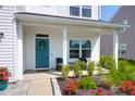 Cozy front porch showcasing a teal door with a wreath, seating, and lush landscaping in a charming setting at 408 Trevi Ln, Summerville, SC 29486