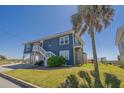 Charming blue beach home featuring elevated construction, a yard and ample space underneath at 412 Palmetto Blvd, Edisto Island, SC 29438
