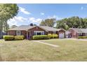 Beautiful brick home with a lush green lawn, mature trees, and an attached garage at 5029 Victoria Ave, North Charleston, SC 29405