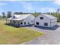 Beautiful farmhouse-style exterior elevation with white siding, metal roof, large covered porch, and detached garage at 733 Oakridge View Trl, Ridgeville, SC 29472