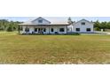 Front view of charming modern farmhouse with a covered porch, white siding, metal roof, and lush green lawn at 733 Oakridge View Trl, Ridgeville, SC 29472