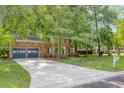 Traditional brick home featuring an attached two-car garage and an expansive driveway lined by a verdant lawn at 103 Sylvan Ter, Summerville, SC 29485