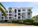 A building with balconies and windows is surrounded by palm trees and lush green landscaping in a coastal setting at 1140 Ocean Blvd # 201, Isle of Palms, SC 29451