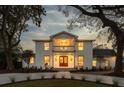 Elegant two-story home with a white brick facade, balcony, and warm interior lighting at twilight at 19 Ponce De Leon Ave, Charleston, SC 29407