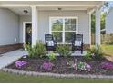 Inviting front porch featuring rocking chairs, a decorative flowerbed, and a black front door at 2016 Elvington Rd, Johns Island, SC 29455