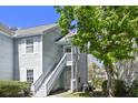 Light-blue two-story condo featuring a welcoming entrance with stairs, a door wreath, and lush landscaping at 2030 Coldspring Dr # 708, North Charleston, SC 29406
