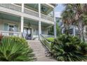 Inviting front porch with ceiling fans and ample seating, with lush landscaping offering curb appeal and shade at 2522 Daniel Island Dr, Daniel Island, SC 29492