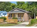 Quaint brick home featuring a covered porch with wooden columns and a modern horizontal-plank fence at 2957 Alabama Dr, North Charleston, SC 29405