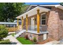 Charming brick home featuring a cozy covered porch with white railing and green landscaping at 2957 Alabama Dr, North Charleston, SC 29405