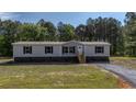 Inviting single-story home with gray siding and black shutters, complemented by a well-kept lawn and gravel driveway at 314 Hickory Nut Way, Cross, SC 29436