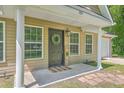Welcoming front entrance with black door, decorative wreath, and 'HOME' sign, framed by white columns and green windows at 333 Price St, Goose Creek, SC 29445