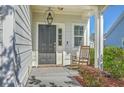Charming front porch with a rocking chair next to a black door with a hanging lantern light fixture at 508 Alderly Dr, Moncks Corner, SC 29461