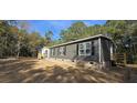 Side view of a single-story home with dark siding and a brick foundation at 945 Tiger Loop, Saint Stephen, SC 29479