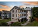 Striking three-story home with double porches, a two-car garage and sunset sky at 118 Wando Reach Rd, Wando, SC 29492