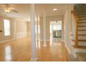 Spacious living room with hardwood floors, columns, and stairs leading to the second level with a kitchen in view at 120 Full Moon Ct, Ladson, SC 29456