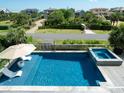 Relaxing pool and hot tub area with lounge chairs, umbrella, and lush green landscaping at 124 Charleston Blvd, Isle of Palms, SC 29451