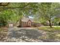 Full front exterior of brick home with a detached garage, driveway and mature tree coverage at 13 Charlestowne Rd Rd, Charleston, SC 29407