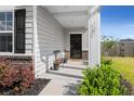 Inviting front porch featuring a black metal bench, potted plants, and a stylish welcome mat at 131 Beargrass Ln, Summerville, SC 29486