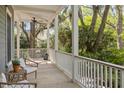 Relaxing porch with ceiling fan, white railings, and comfortable seating overlooking a lush landscape at 2187 Saint James Dr, Charleston, SC 29412