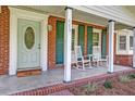 Inviting front porch with rocking chairs, brick accents, and a decorative front door with glass accents at 403 Forest Cir, Summerville, SC 29483