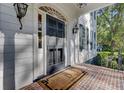 Inviting front porch with brick flooring leading to a black front door with glass panels and stylish sconces at 418 W Carolina Ave, Summerville, SC 29483