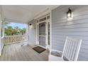 Covered porch with rocking chairs and a view of tropical palm trees at 67 Lost Village Trl # 4, Edisto Island, SC 29438