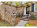 Brick home with a black front door, landscaping, and brick privacy wall at 1383 W Lenevar Dr, Charleston, SC 29407