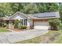 View of a well-maintained home with a two-car garage and solar panels on a lush, green lot at 1705 Sulgrave Rd, Charleston, SC 29414