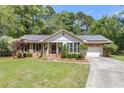 View of charming brick home with solar panels, attached garage, manicured lawn, and inviting curb appeal at 1705 Sulgrave Rd, Charleston, SC 29414