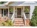 Cozy front porch with rocking chairs, decorative plants, brick stairs, and charming curb appeal at 1705 Sulgrave Rd, Charleston, SC 29414