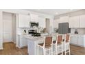 Bright kitchen boasts white cabinets, stainless appliances, and a center island with seating at 206 Belfort Way, Summerville, SC 29486