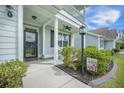 Inviting front porch area with rocking chairs, lush greenery, and a charming lantern post at 419 Whispering Breeze Ln, Summerville, SC 29486