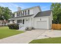 Charming two-story home with white siding, black shutters, a well-manicured lawn, and attached garage at 4301 Trevor St, North Charleston, SC 29420