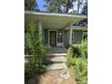 Close up of a front porch with concrete steps leading up to the front door in a home surrounded by overgrown foliage at 436 W Butternut Rd, Summerville, SC 29483