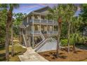 Beautiful two-story beach home with double porches, American flag, and lush tropical foliage at 607 Jungle Rd, Edisto Beach, SC 29438