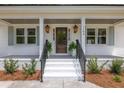 Inviting front porch with classic lanterns, a striking front door, and decorative plantings at 1199 Island View Dr, Mount Pleasant, SC 29464