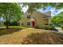 Charming tan home with a red front door, green grass, and mature trees at 247 Darcy Ave, Goose Creek, SC 29445
